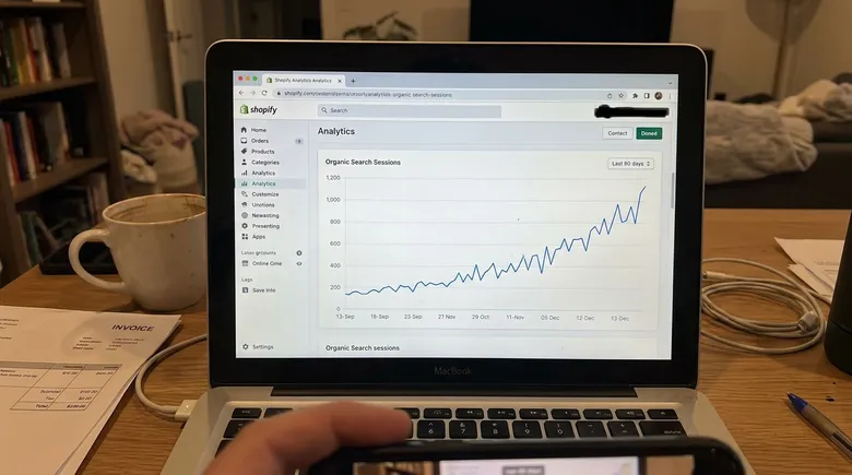 SCENE: Close-up of a Shopify analytics screen showing organic search traffic line sharply climbing over a 90-day period